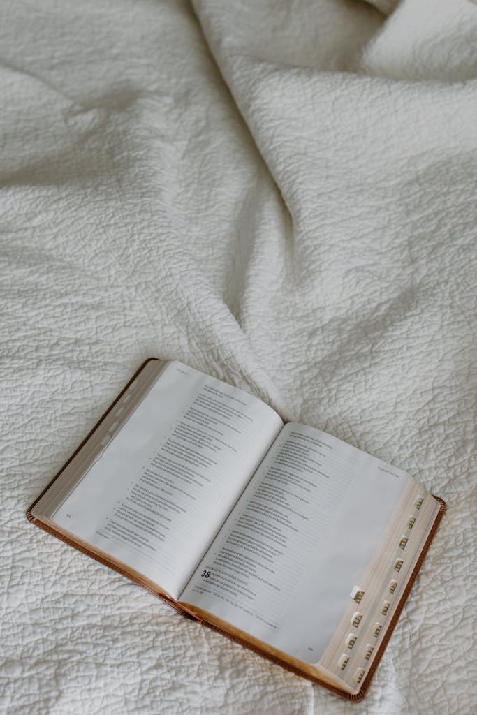 An open Bible lying on a white textured fabric, showcasing religious scripture vividly.