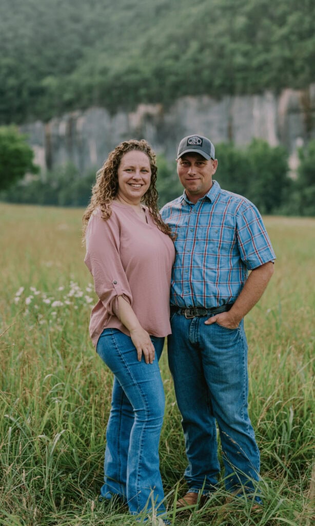 Blog author Brittany standing in a field with her husband, facing the camera with a bluff and trees in the background.